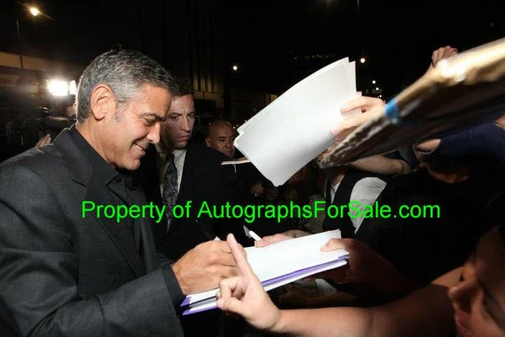 Celebrity signing autographs for fans at night, authentic signed memorabilia event