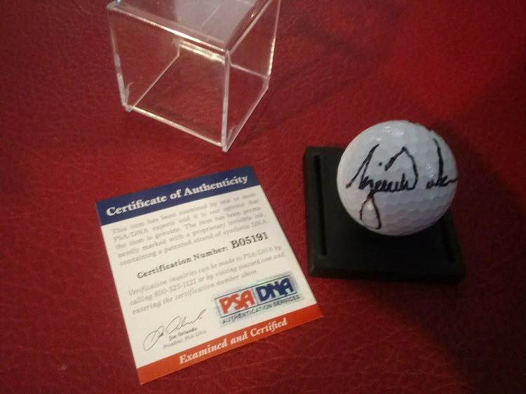 Signed golf ball with Certificate of Authenticity and PSA DNA authentication on red background