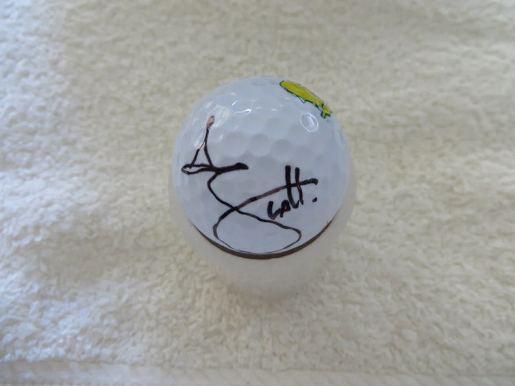Signed golf ball with black signature and Masters logo on a white towel background