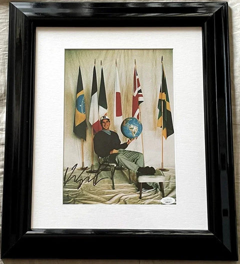 Framed autographed photo of man holding globe, sitting with international flags behind