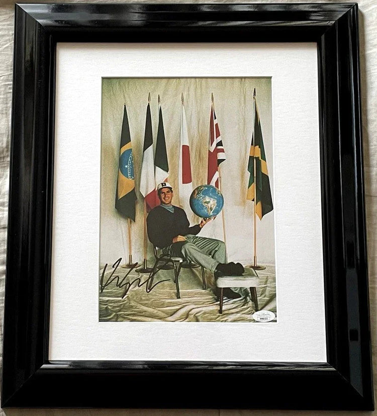 Framed autographed photo of man holding globe, sitting with international flags behind