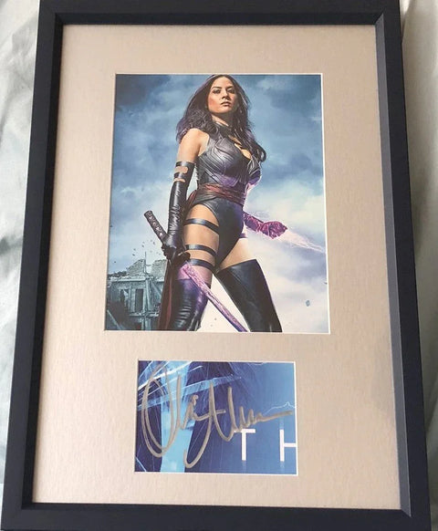 Framed signed memorabilia featuring a female superhero with sword in costume, autograph displayed below.