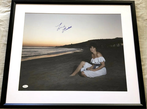 Framed signed photo of a woman in a white dress sitting on a beach at sunset.