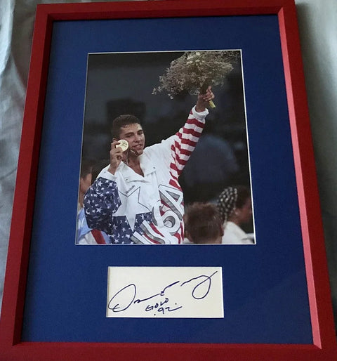 Framed autographed photo of a boxer wearing USA jacket holding up an Olympic gold medal.