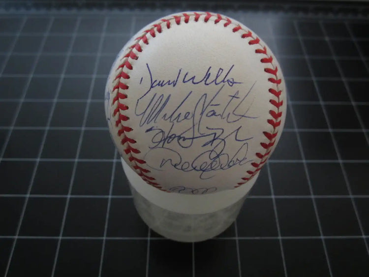 Official Major League Baseball with multiple autographs and red stitching on display stand.