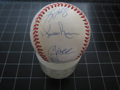 Official baseball featuring multiple autographs in blue ink, displayed on a grid surface