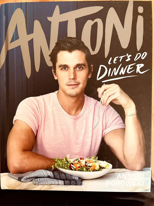 Cookbook cover featuring Antoni Porowski in a pink shirt with a fork and salad, titled Let's Do Dinner