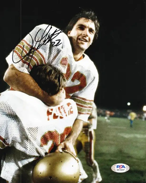 Signed football photo with player in white jersey being lifted by teammate, PSA authenticated
