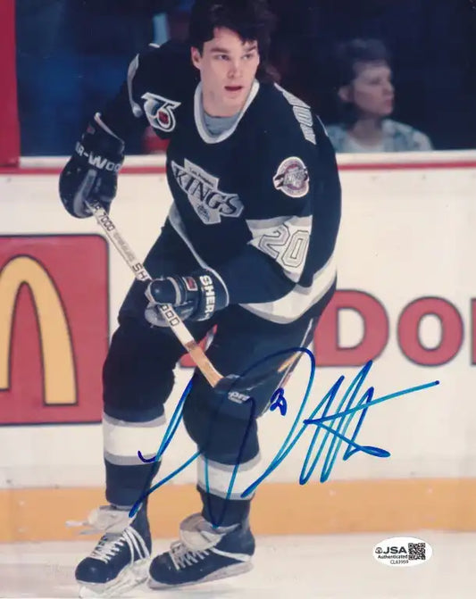 Autographed photo of hockey player in Kings jersey, holding stick on ice, signed in blue ink.