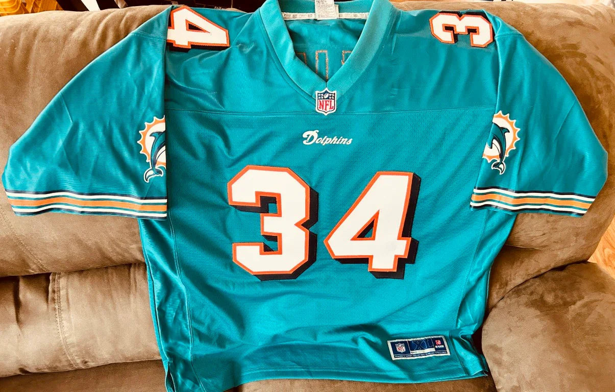 Miami Dolphins NFL jersey number 34 with Dolphins logo on sleeves, laid on brown couch