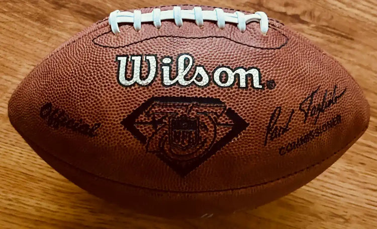Wilson NFL 75th Anniversary official football with printed signatures on wooden surface