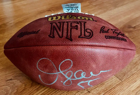 NFL Wilson football with visible autograph on wood surface, signed sports memorabilia.