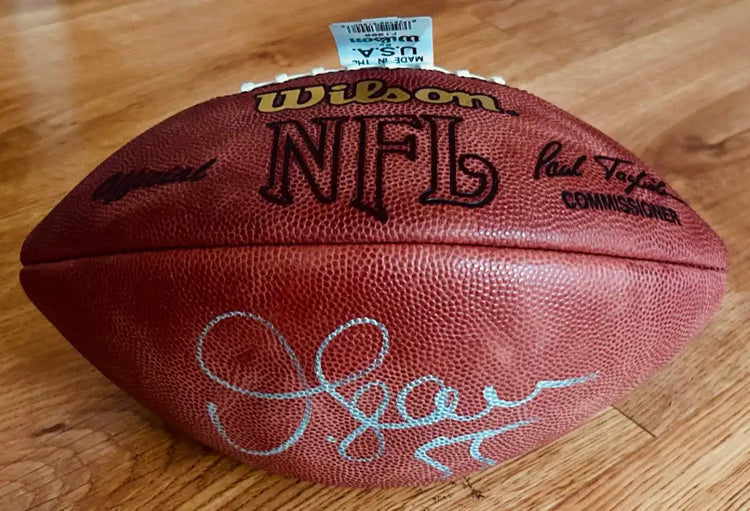 NFL Wilson football with visible autograph on wood surface, signed sports memorabilia.