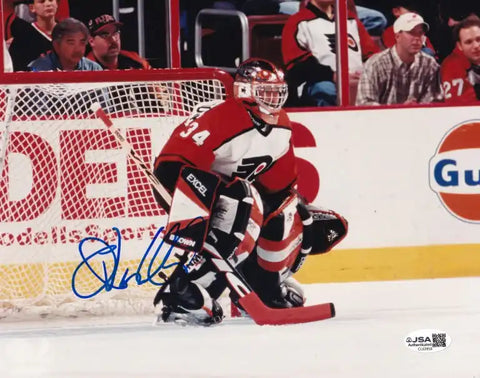 Autographed NHL goalie photo in red and white uniform, JSA certified, on ice during game