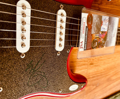 Signed red electric guitar with JSA authentication, featuring autograph on pickguard and certification card.